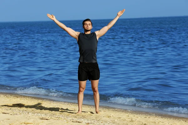 Ung man sportiga gör övning på stranden — Stockfoto