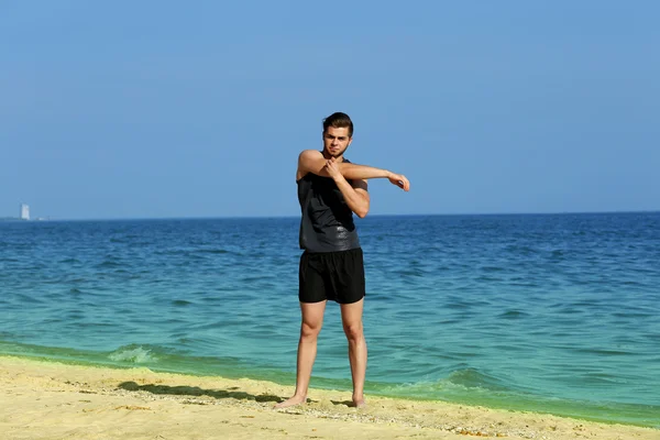 Giovane sportivo facendo esercizio sulla spiaggia — Foto Stock