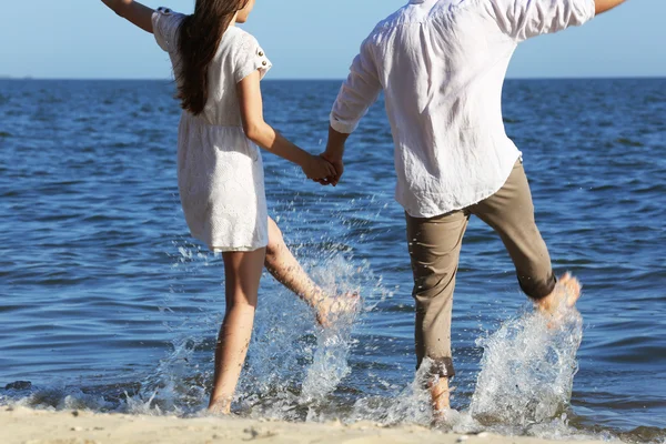 Ungt par hålla händerna på stranden — Stockfoto