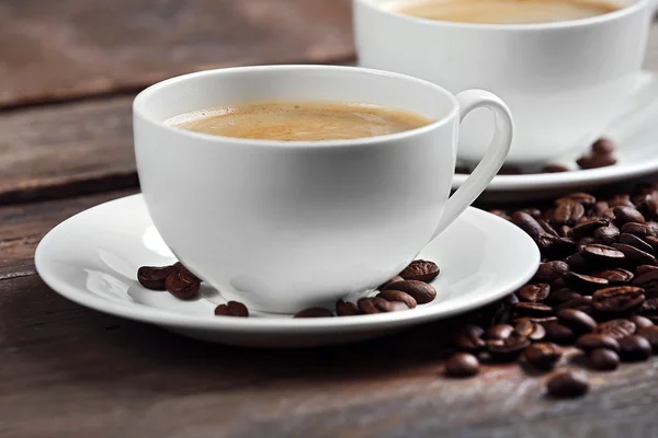 Cups of coffee and beans on wooden table close up — Stock Photo, Image