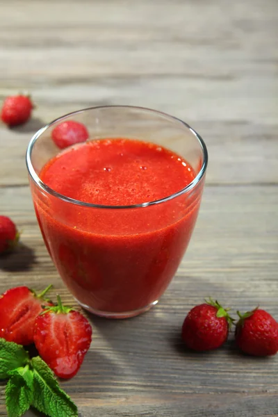 Glas av jordgubb smoothie med bär på träbord nära håll — Stockfoto