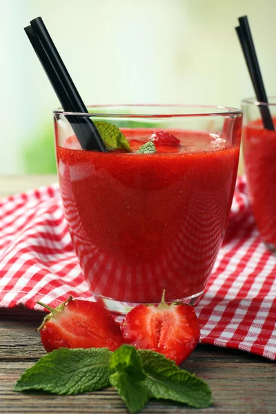 Glasses of strawberry smoothie with berries on bright background — Stock Photo, Image