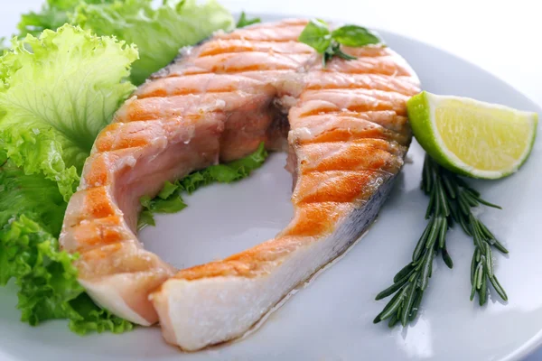 Вкусный лосось на гриле с лаймом и зеленью на тарелке — стоковое фото