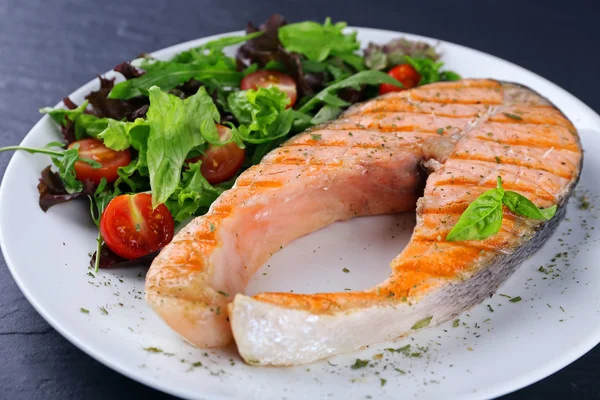 Salmão grelhado saboroso com salada na mesa de perto — Fotografia de Stock