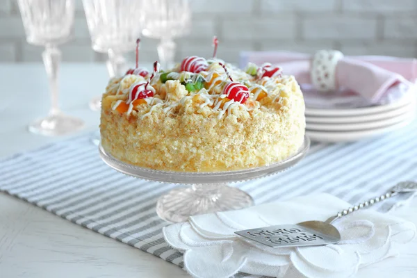 Smör tårta med körsbär på stativ och dukningen på ljus bakgrund — Stockfoto