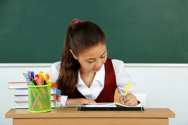 Beautiful little schoolgirl in classroom near blackboard — Stock Photo, Image