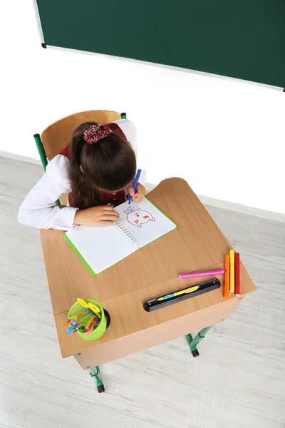 Bela colegial em sala de aula e desenha em caderno — Fotografia de Stock