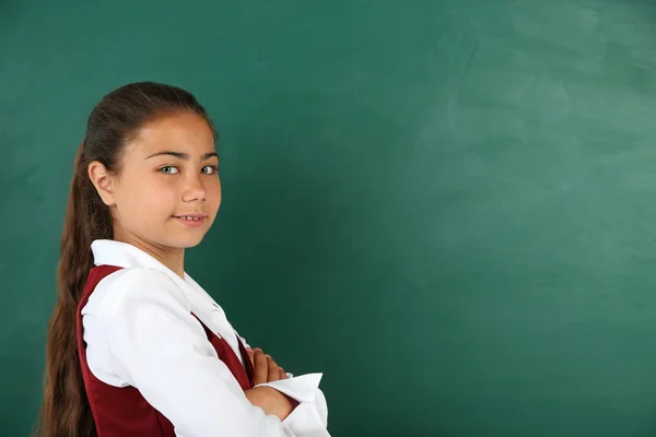 Belle petite fille debout près du tableau noir dans la salle de classe — Photo