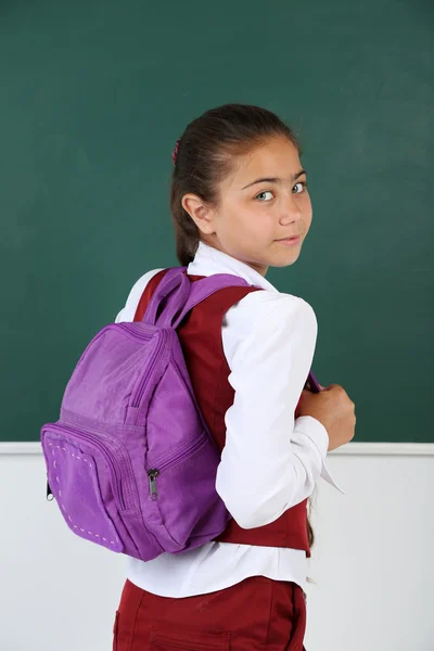 Hermosa niña de pie cerca de pizarra en el aula —  Fotos de Stock