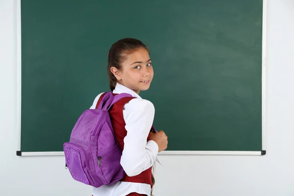 漂亮的小女孩，站在教室里的黑板旁边 — 图库照片