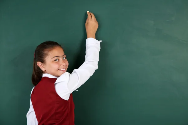 Vacker liten flicka skriver på tavlan i klassrummet — Stockfoto