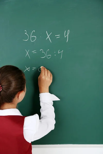Beautiful little girl writes on blackboard in classroom — Stock Photo, Image
