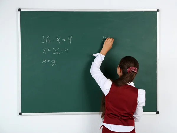 Hermosa niña escribe en pizarra en el aula —  Fotos de Stock