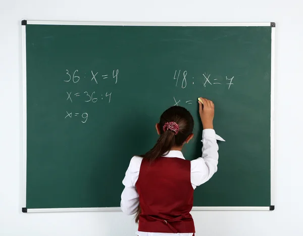 Schönes kleines Mädchen schreibt auf Tafel im Klassenzimmer — Stockfoto