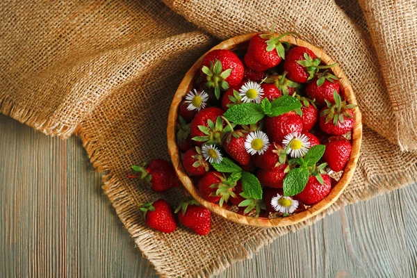 Fresas rojas maduras en canasta de mimbre, sobre fondo de madera — Foto de Stock