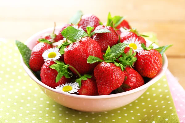 Rode rijpe aardbeien in kom, op een houten achtergrond kleur — Stockfoto