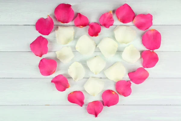 Corazón de pétalos de rosa sobre fondo de madera — Foto de Stock