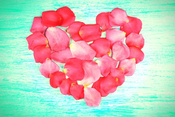 Heart of rose petals on wooden background — Stock Photo, Image