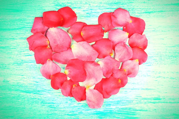 Corazón de pétalos de rosa sobre fondo de madera — Foto de Stock