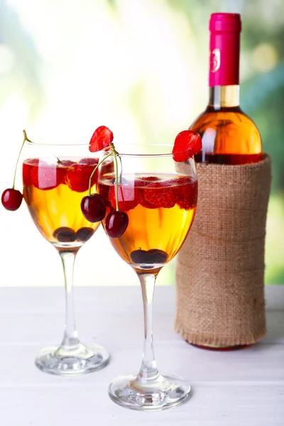 Glasses of wine with berries on light blurred background — Stock Photo, Image