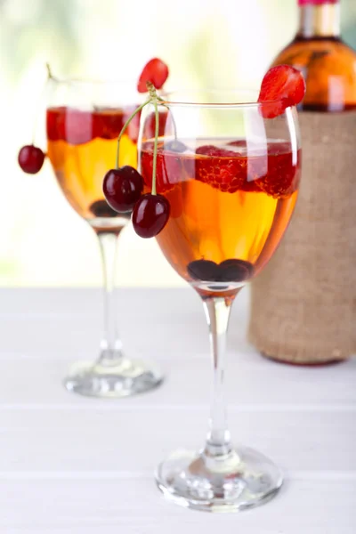 Glasses of wine with berries on light blurred background — Stock Photo, Image