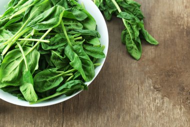 ahşap arka plan üzerinde kase taze ıspanak yaprakları