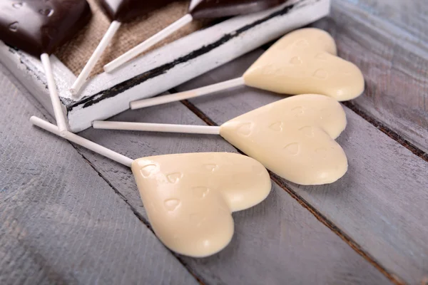 Chocolade hartvormige snoepjes op stokken op houten tafel, close-up — Stockfoto