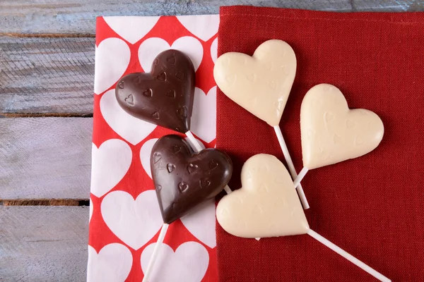 Choklad hjärtformade godis på pinnar på röd Servett, närbild — Stockfoto