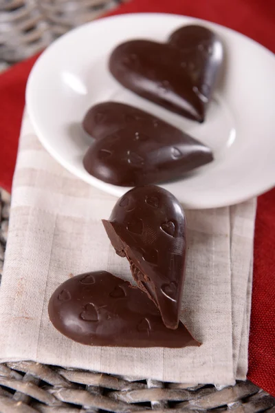 Doces em forma de coração de chocolate em paus em placa branca, close-up — Fotografia de Stock