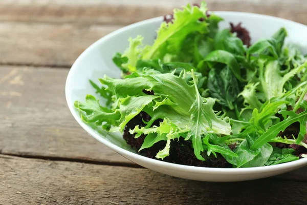 Kase üzerinde ahşap masa, closeup karışık yeşil salata — Stok fotoğraf