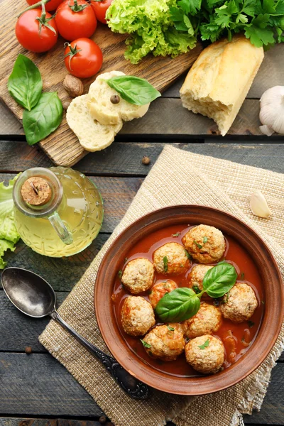 Meat balls with tomato sauce, wooden spoon on wooden background — Stock Photo, Image