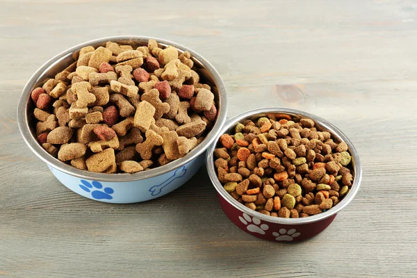 Comida para perros en cuencos sobre mesa de madera —  Fotos de Stock