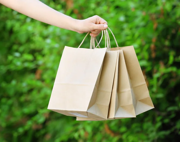 Mão feminina segurando sacos de compras ao ar livre — Fotografia de Stock