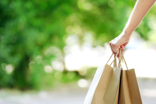 Female hand holding shopping bags outdoors — Stock Photo, Image