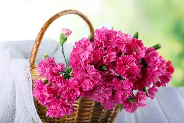 Hermoso ramo de clavel rosa en canasta sobre fondo brillante —  Fotos de Stock