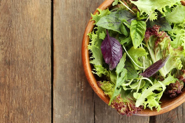 Свежий зеленый салат в миске на деревянном столе вблизи — стоковое фото