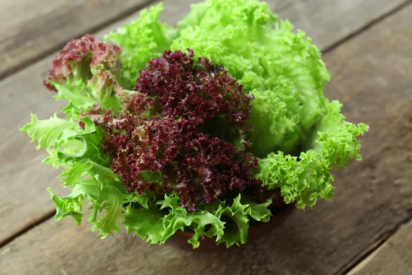 Fresh mixed green salad in bowl on wooden table close up — Stock Photo, Image