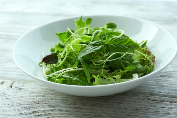 Salada verde mista fresca em tigela na mesa de madeira close-up — Fotografia de Stock