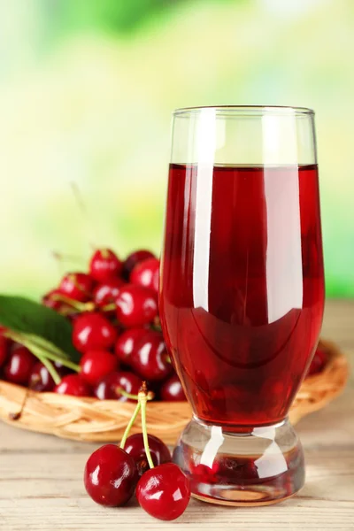 Glass of fresh juice with cherries on bright background — Stock Photo, Image