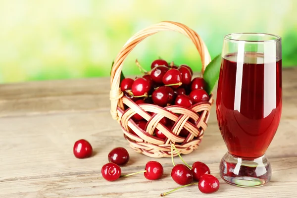 Glass of fresh juice with cherries on bright background — Stock Photo, Image