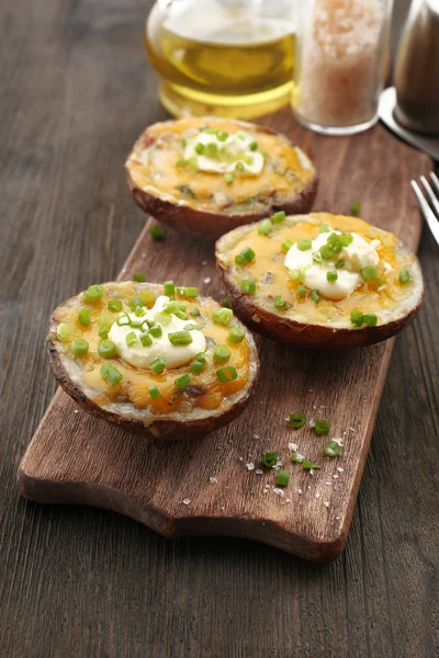 Batata assada com maionese e cebolinha em tábua de corte de madeira, close-up — Fotografia de Stock