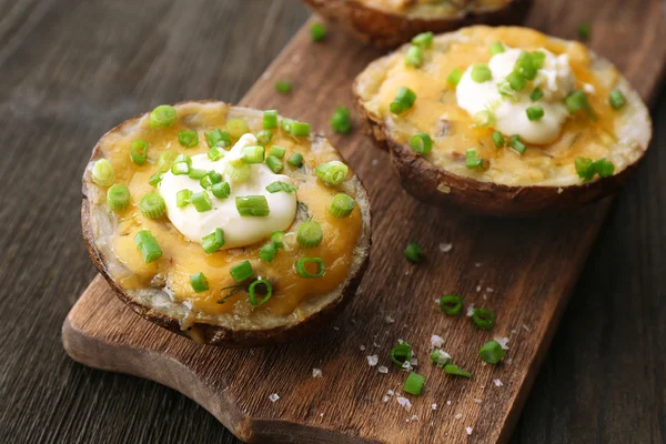Baked potato with mayonnaise and chives on wooden cutting board, closeup — Stock Photo, Image
