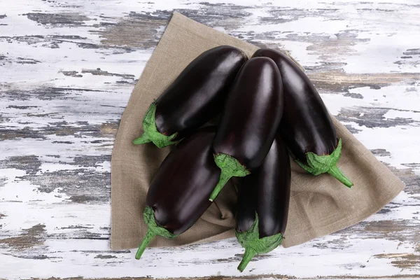 Aubergine fraîche sur sac sur table en bois, vue de dessus — Photo