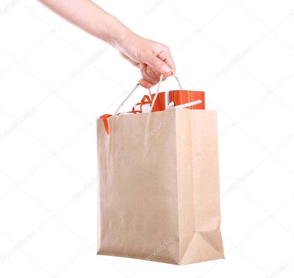 Female hand holding paper bag with present boxes isolated on white
