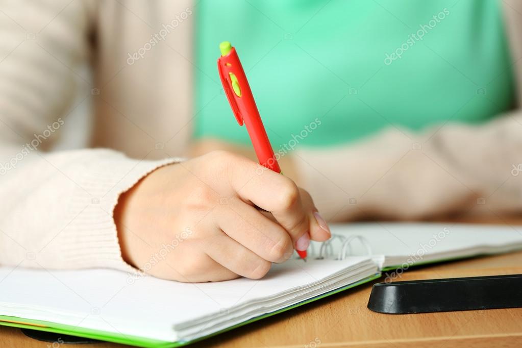 Female hand writing in notebook, close-up