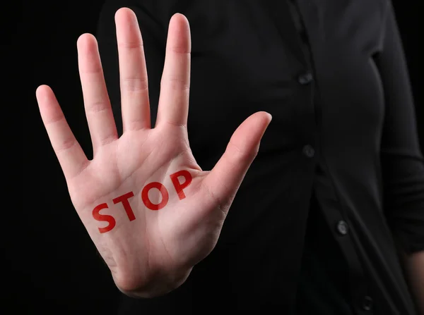 Жіноча рука зі словом STOP на чорному тлі — стокове фото