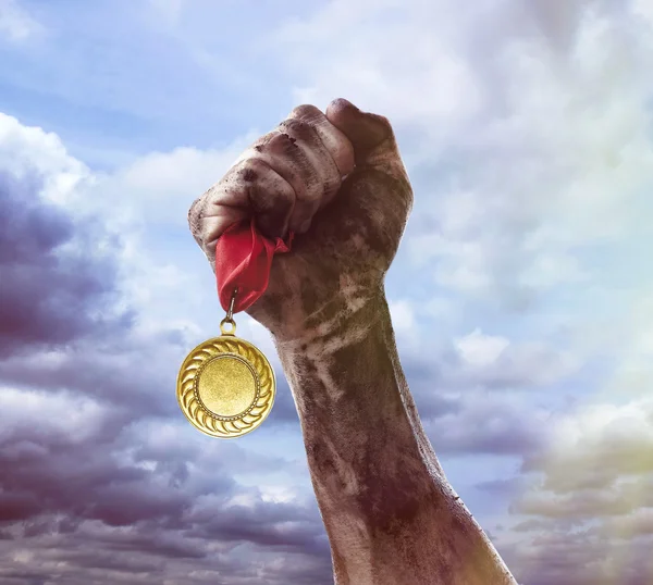 Golden medal in hand on sky background — Stock Photo, Image