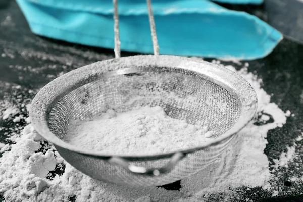 Przesiewanie mąki przez sito na drewnianym stole, zbliżenie — Zdjęcie stockowe