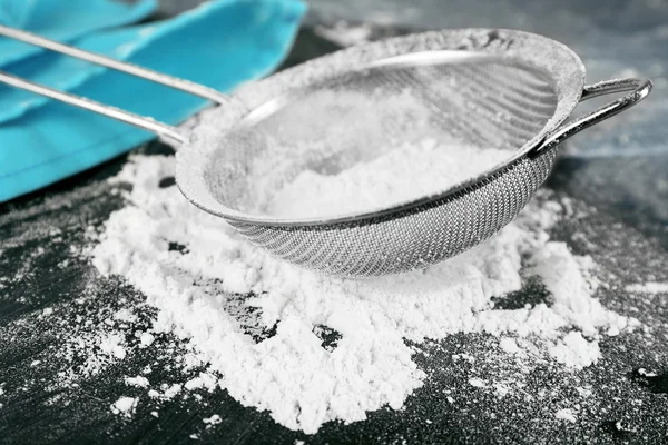 Sifting flour through sieve on wooden table, closeup — Stock Photo, Image