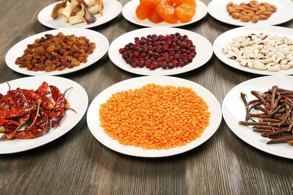 Different products on saucers on wooden table, closeup — Stock Photo, Image